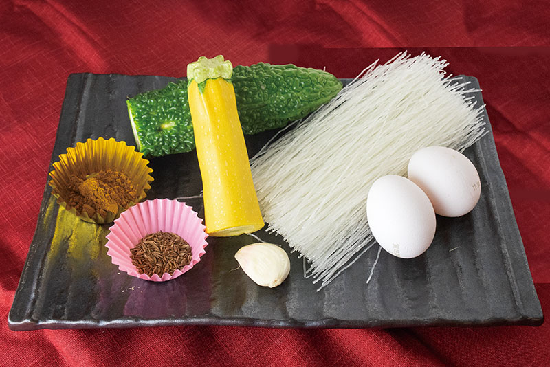 ゴーヤ 1/2本、春雨 100g、卵2個、 ズッキーニ 1/2本、ミニトマト 3個、ニンニク ひとかけ、ローリエの葉 1枚、ミニトマト 【調味料】 クミン 少々、カレーパウダー 小さじ山盛り1、 めんつゆ 小さじ2、和風だしの素 少々